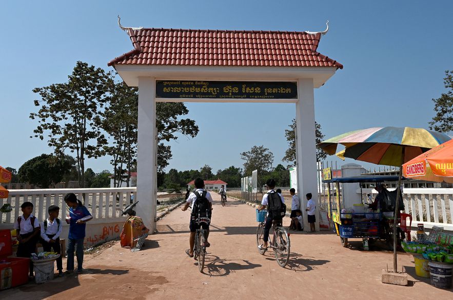 Des élèves arrivent en vélo à l'école de Run Ta Ek, qui accueillent les habitants expulsés de la zone d'Angkor Wat, le 17 janvier 2023 dans la province de Siem Reap, au Cambodge