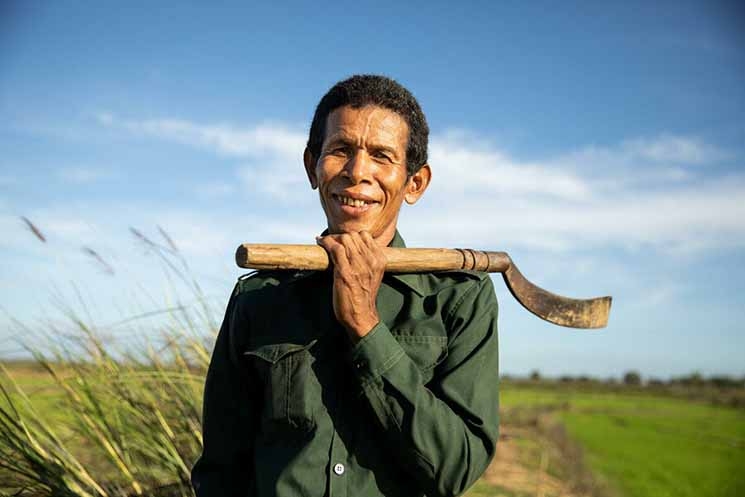Deur Sok clears the area around his rice paddies in Sambour commune, near Kampong Thom. The canal built as part of WFP's climate resilience work helps him keep his crops healthy. Photo: WFP/Samantha Reinders