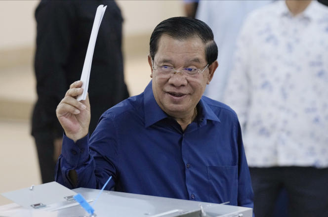 Le premier ministre cambodgien, Hun Sen, du Parti du peuple cambodgien (PPC), lève un bulletin de vote avant de voter dans un bureau de vote à Takhmua, dans la province de Kandal, au sud-est de Phnom Penh, au Cambodge, le 23 juillet 2023.