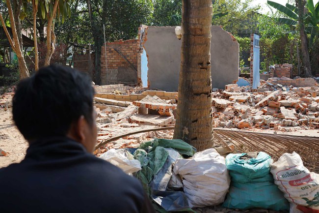 Un homme devant une maison détruite sur le site du patrimoine mondial d'Angkor, mars 2023. © Amnesty International